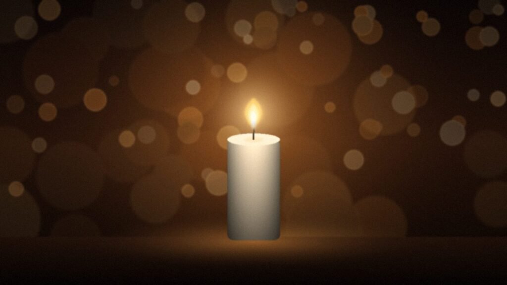 A single lit candle glowing warmly among soft golden bokeh lights